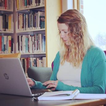 Woman working on laptop in the library's nonfiction section