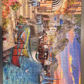 Cafe on water with boats, sunset and mountains in background
