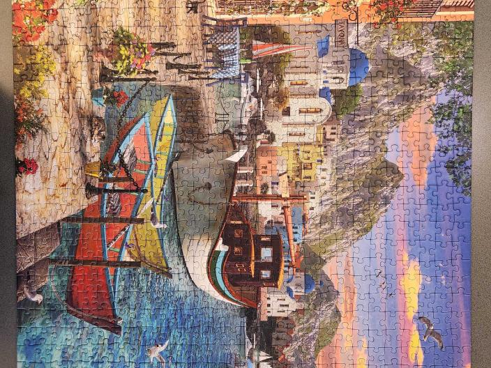 Cafe on water with boats, sunset and mountains in background