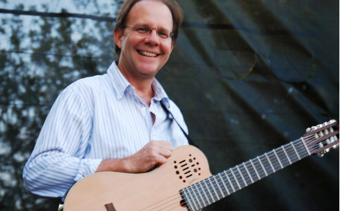 David Newsam standing on stage with guitar in hand