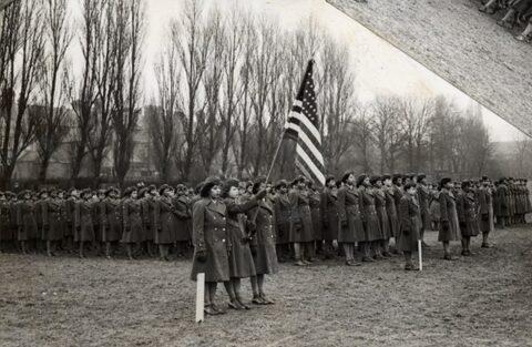Military Service Members standing behind the American Flag