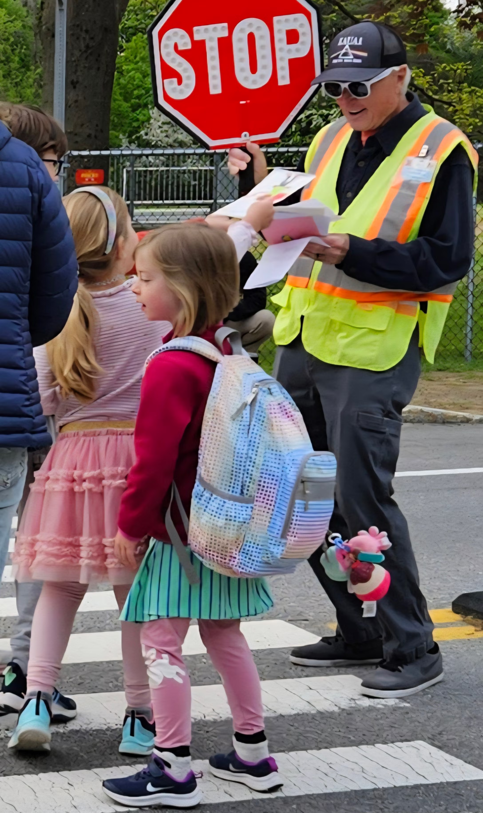 A crossing guard with students in the crosswalk
